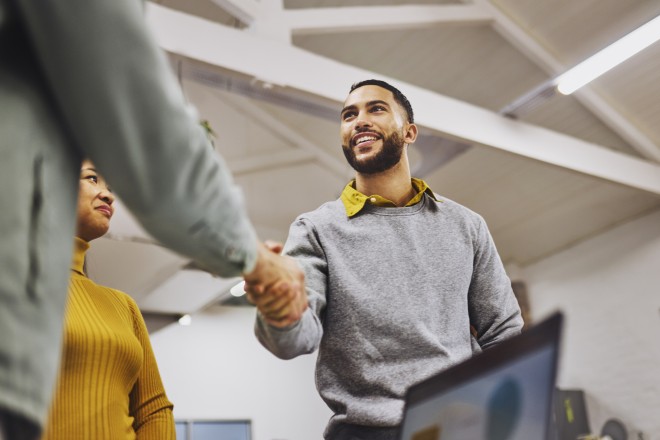 Low angle view of cheerful executive shaking hands with colleague in office