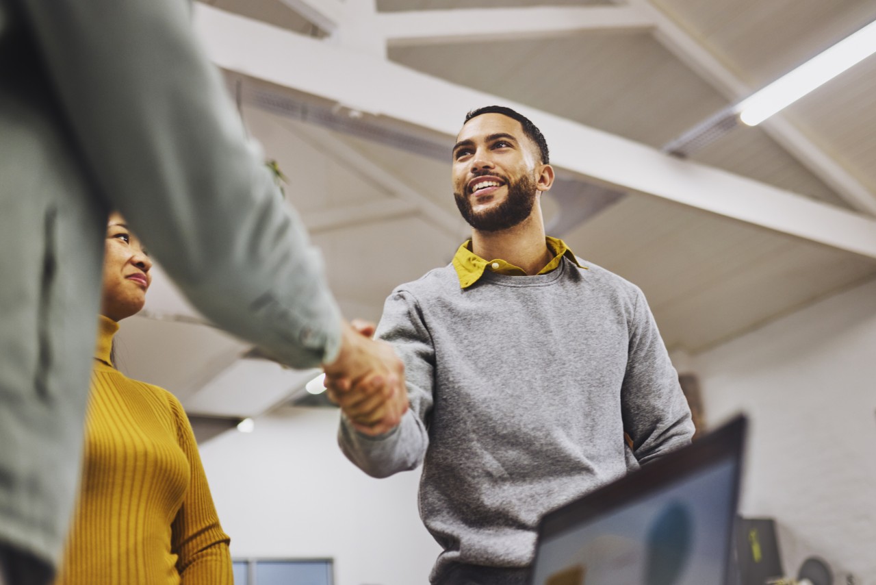 Low angle view of cheerful executive shaking hands with colleague in office