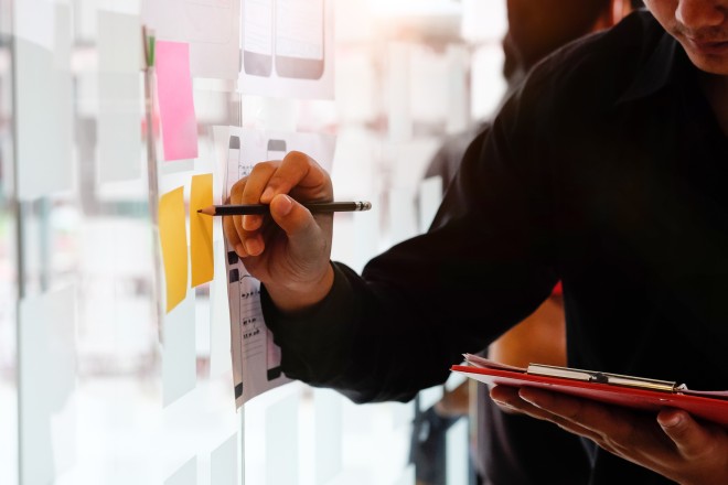 A man working with creative and using stocky note paper on glass wall